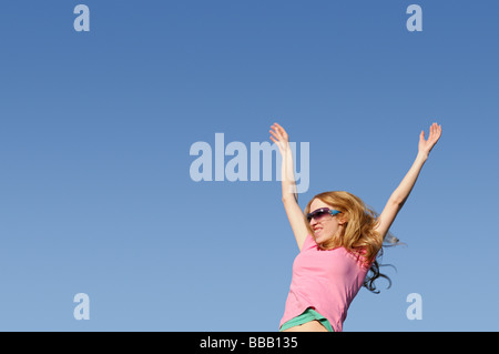 Frau mit vor einem blauen Himmel erhobenen Armen Stockfoto