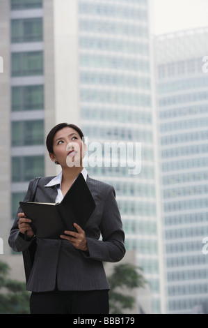 Chinesische Geschäftsfrau hält einen Ordner, da sie in der Stadt, China steht Stockfoto