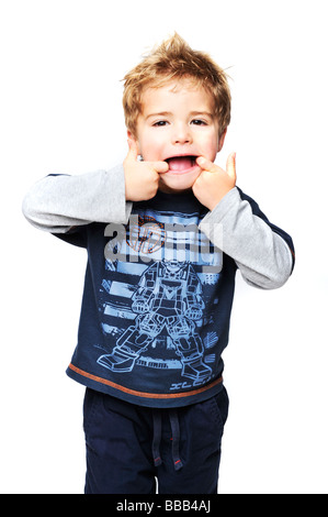 Junge 4 Jahre alt mit blonden Haaren spikey, zieht ein Gesicht zur Kamera in blau oben auf ein weißes Studio-Hintergrund Stockfoto