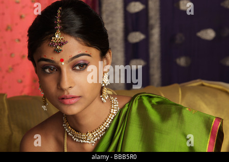 Frau trägt Sari, umgeben von Sari-Stoff, verziert mit Henna-Tattoos, Schmuck und bindi Stockfoto