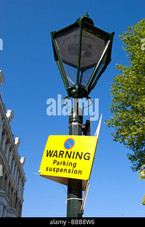 viktorianischen Stil Laternenpfahl mit Parkplatz Aussetzung Warnschild, vor einem blauen Himmel und Häuser typisch für Kensington, London zu sehen Stockfoto