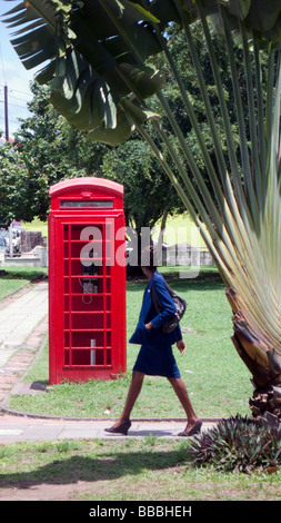 Frau Fußgänger Spaziergänge vorbei an alten roten britischen Telefon box Unabhängigkeit Square Basseterre, St. Kitts Stockfoto