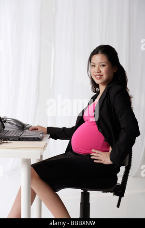 Profil von schwangeren Geschäftsfrau am Schreibtisch Stockfoto