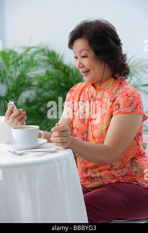 Reife Frau mit Tee und Musik hören Stockfoto