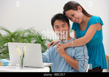 Junge Frau stützte sich auf die Schulter des Mannes am computer Stockfoto
