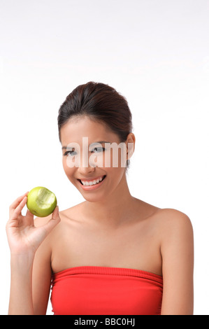 Junge Frau lächelt in die Kamera hält Apfel Stockfoto