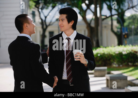 Zwei Männer in Anzügen einander grüßen und Handschlag im park Stockfoto