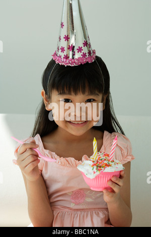 Geburtstagskind mit Cupcake und Löffel auf der Seite in die Kamera Lächeln Stockfoto