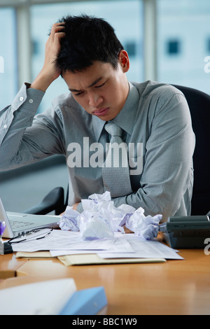 Ein Mann sieht gestresst, als er an seinem Schreibtisch arbeitet Stockfoto