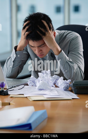 Ein Mann sieht gestresst, als er an seinem Schreibtisch arbeitet Stockfoto