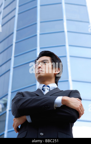Ein Mann mit einem Anzug steht vor einem Hochhaus Stockfoto