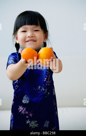 Ein kleines Mädchen hält zwei Mandarinen Stockfoto