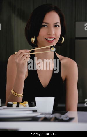 Eine Frau schaut in die Kamera, wie sie Sushi isst Stockfoto