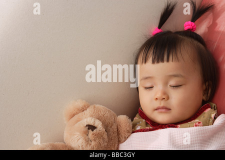 Babymädchen schläft mit Teddybär Unterdecke Stockfoto