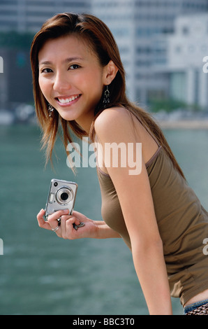 Frau mit Digitalkamera, lächelnd in die Kamera Stockfoto
