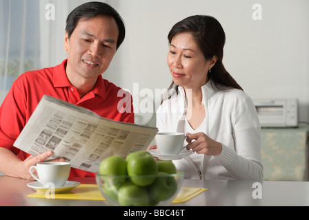 Älteres Paar zu Hause, auf der Suche bei Zeitung und Kaffee Stockfoto