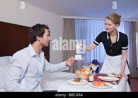 Zimmermädchen servieren Geschäftsmann in seinem Zimmer Stockfoto