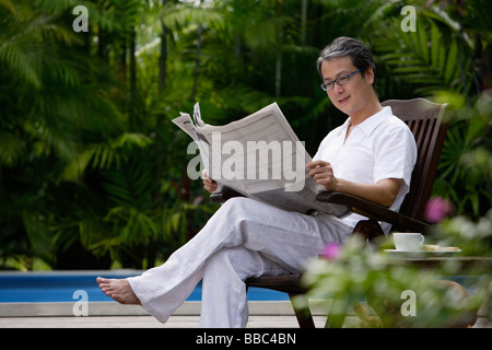 Reifer Mann sitzen im Freien, lesen Zeitung Stockfoto