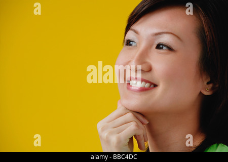 Junge Frau mit Hand am Kinn, Lächeln Stockfoto
