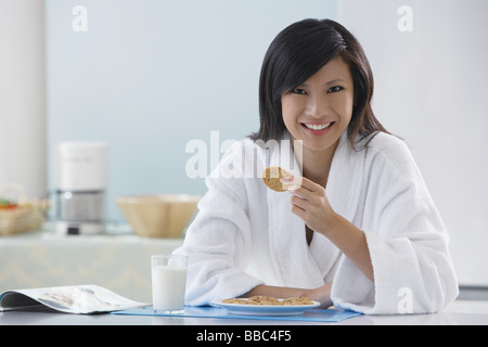 Frau in der Küche tragen Bademantel, mit Kochen, lächelnd in die Kamera, lesen Magazin Stockfoto