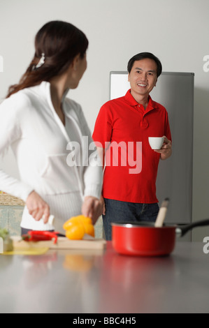 Reife Frau in der Küche und bereitet eine Mahlzeit, drehen, um den Mann hinter ihr Stand aussehen Stockfoto