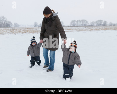 Frau zu Fuß mit Zwillingssöhne im Schnee Stockfoto