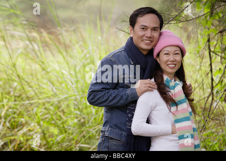 Mann und Frau mit Hut und Schals, stehen draußen in der Natur, in die Kamera Lächeln Stockfoto