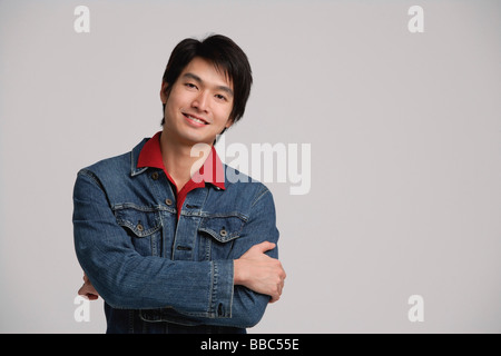 Mann in Jeansjacke, Arme verschränkt Stockfoto