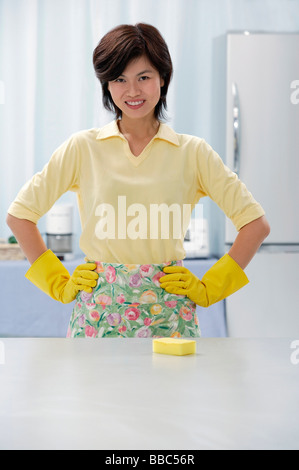 Frau in Küche, tragen von Handschuhen und Schürze, Hände auf den Hüften Stockfoto