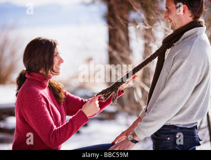 Lächelnde Frau ziehen am Mannes Schal Stockfoto