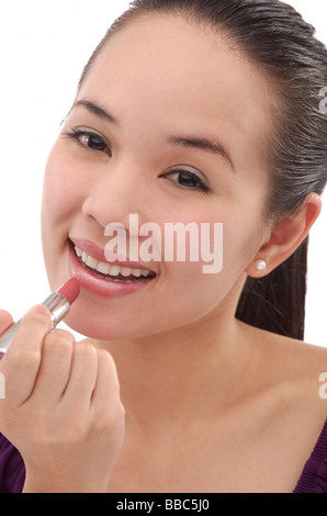 Junge Frau Auftragen von Lippenstift, Lächeln Stockfoto