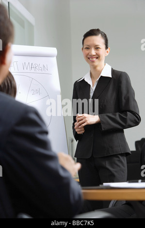 Geschäftsfrau stehen neben Flipchart, lächelnd an Kollegen Stockfoto