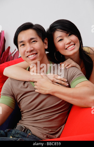 Paar lächelnd in die Kamera, Frau umarmen Mann von hinten Stockfoto