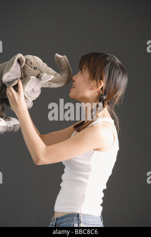 Junge Frau küssen Stofftier Elefant Stockfoto