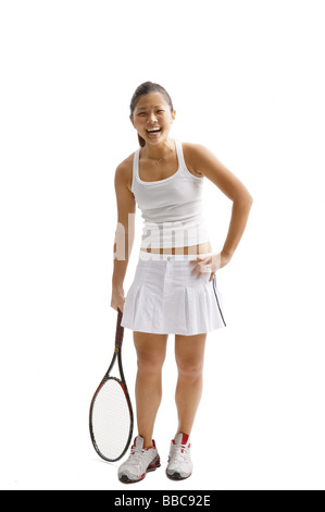 Junge Frau in Tennis-Outfit, stehend mit Tennisschläger Stockfoto