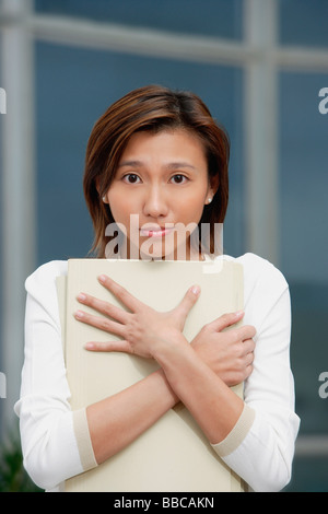 Weibliche Führungskraft umarmt Ordner, traurigen Ausdruck Stockfoto