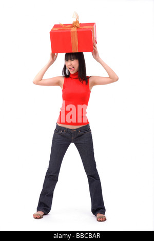 Junge Frau, die große rote Geschenkbox auf dem Kopf balancieren Stockfoto