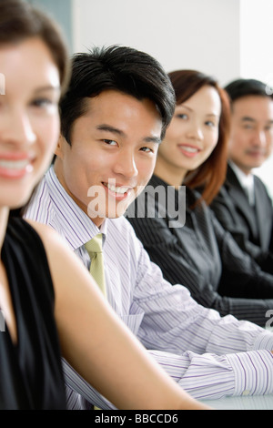 Führungskräfte, die sitzen in einer Reihe, Blick in die Kamera, Lächeln, Porträt Stockfoto