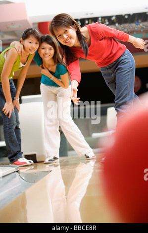 Drei Frauen auf einer Bowlingbahn, Bowling-Kugel im Vordergrund Stockfoto