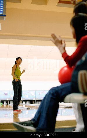 Frau auf Bowling-Bahn, drehen um Freunde hinter ihr zu betrachten Stockfoto