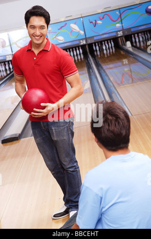 Mann, der Bowling-Kugel, stehend in der Kegelbahn Stockfoto