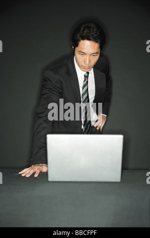 Geschäftsmann, stehen, Blick auf Laptop auf Tisch Stockfoto