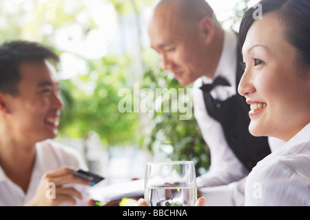 Frau, wegsehen, Man zahlt mit Kreditkartenabrechnung im Hintergrund Stockfoto