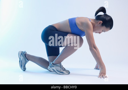 Frau kniet am Ausgangsposition, Seitenansicht Stockfoto