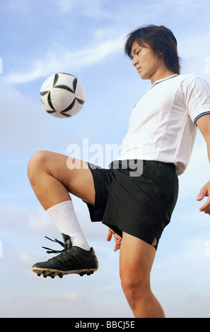 Mann Prellen Fußball auf Knie Stockfoto