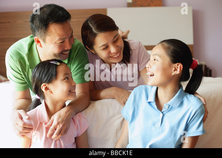 Vater und Mutter mit zwei Töchtern im Schlafzimmer Stockfoto