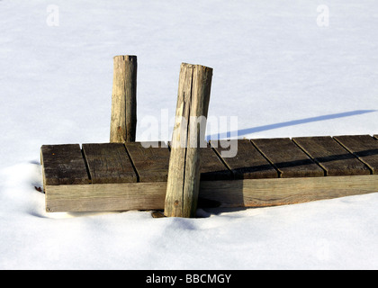 Hölzerne Dock in zugefrorenen, verschneiten See Stockfoto
