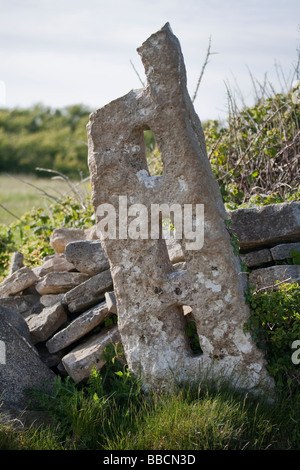 Eine verlassene steinerne Säule und eingestürzten Trockenmauer stehen in einem Feld von Dorset Stockfoto