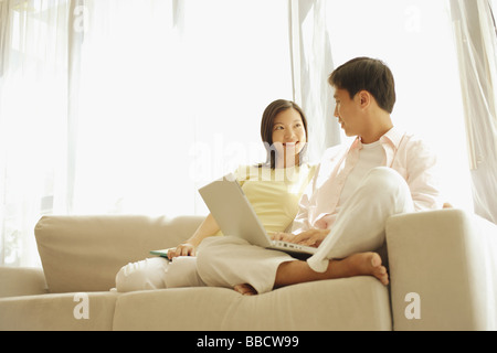 Junges Paar sitzt auf dem Sofa, mit laptop Stockfoto