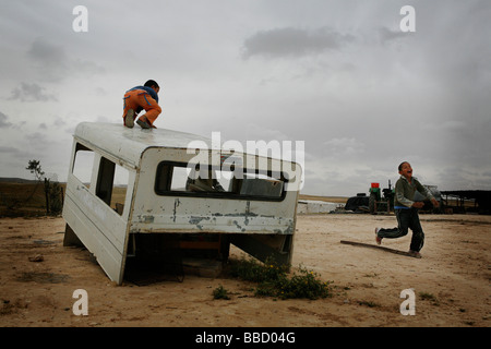 Kinder spielen mit dem Skelett eines Autos in das Dorf El Araqeeb, Israel Stockfoto